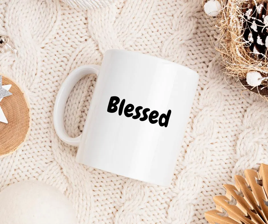 White mug with 'Blessed' text on a textured beige surface