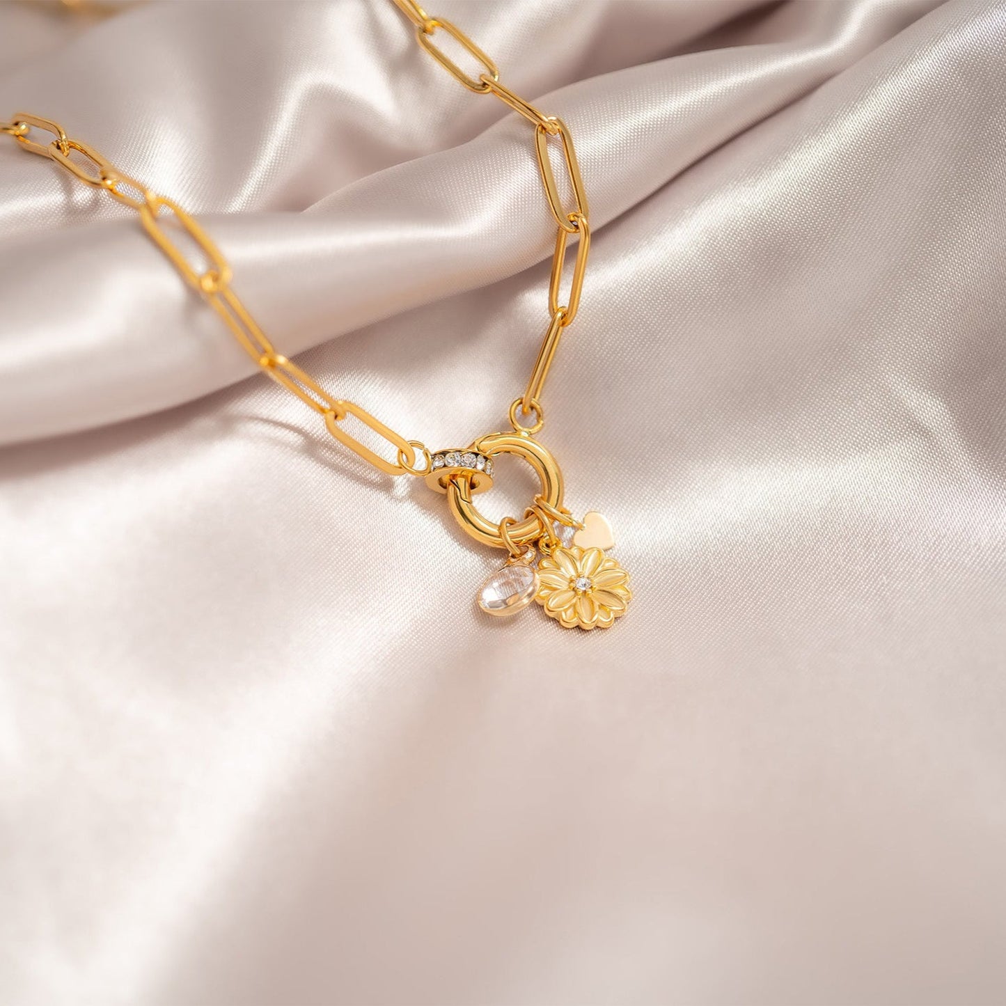 Gold necklace with floral pendant on a satin surface