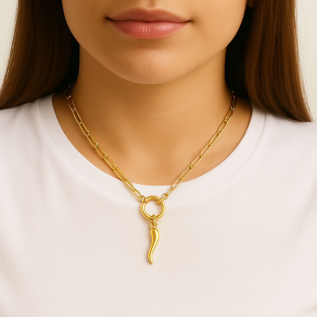 Gold paperclip necklace with an Italian horn pendant worn by a person on a white background