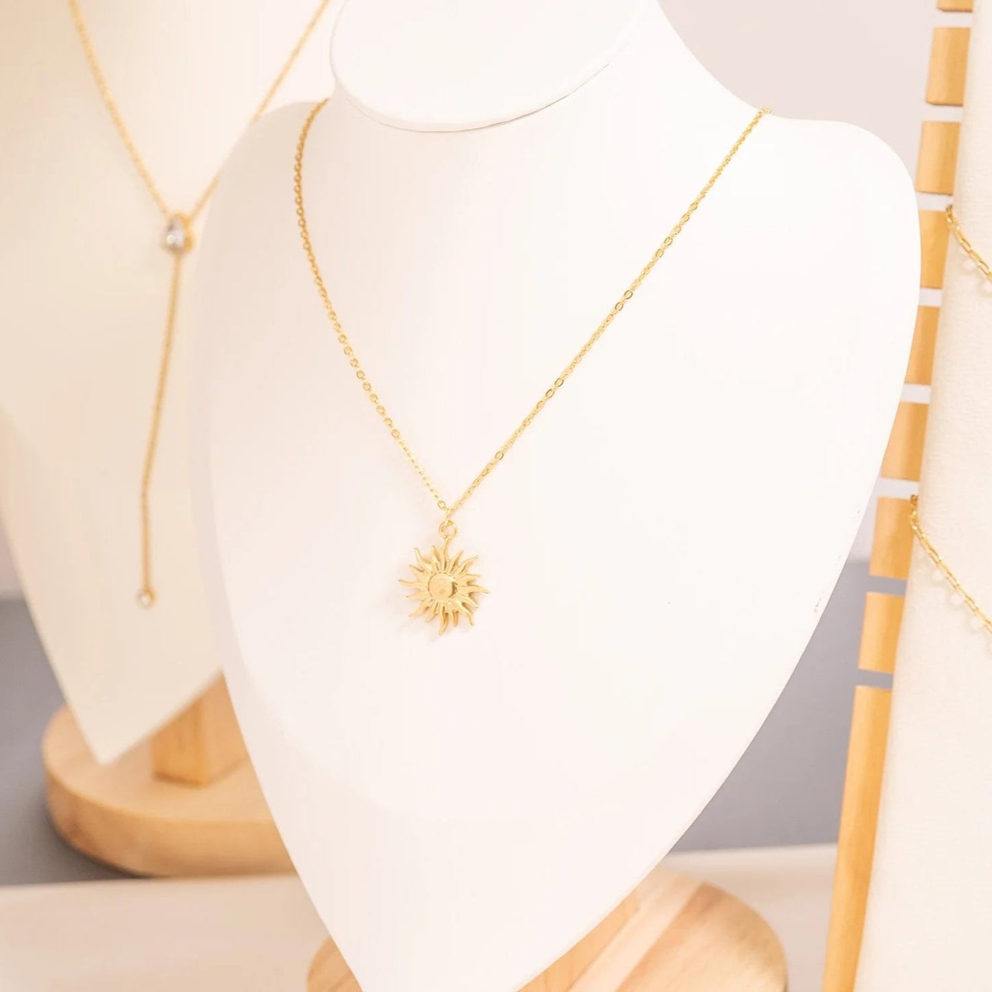 Gold necklace with a sun pendant on a mannequin bust.