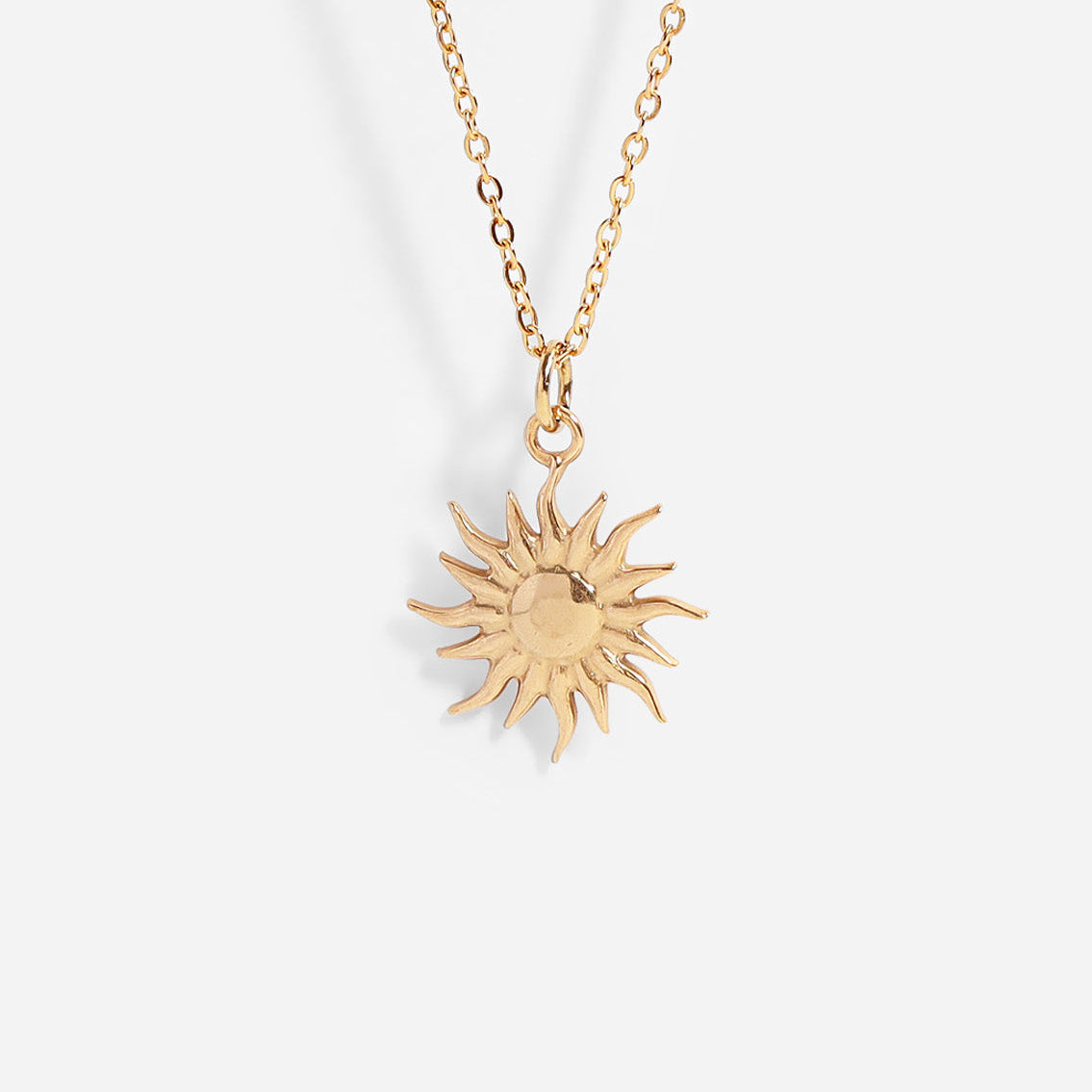 Gold sun-shaped pendant necklace on a white background