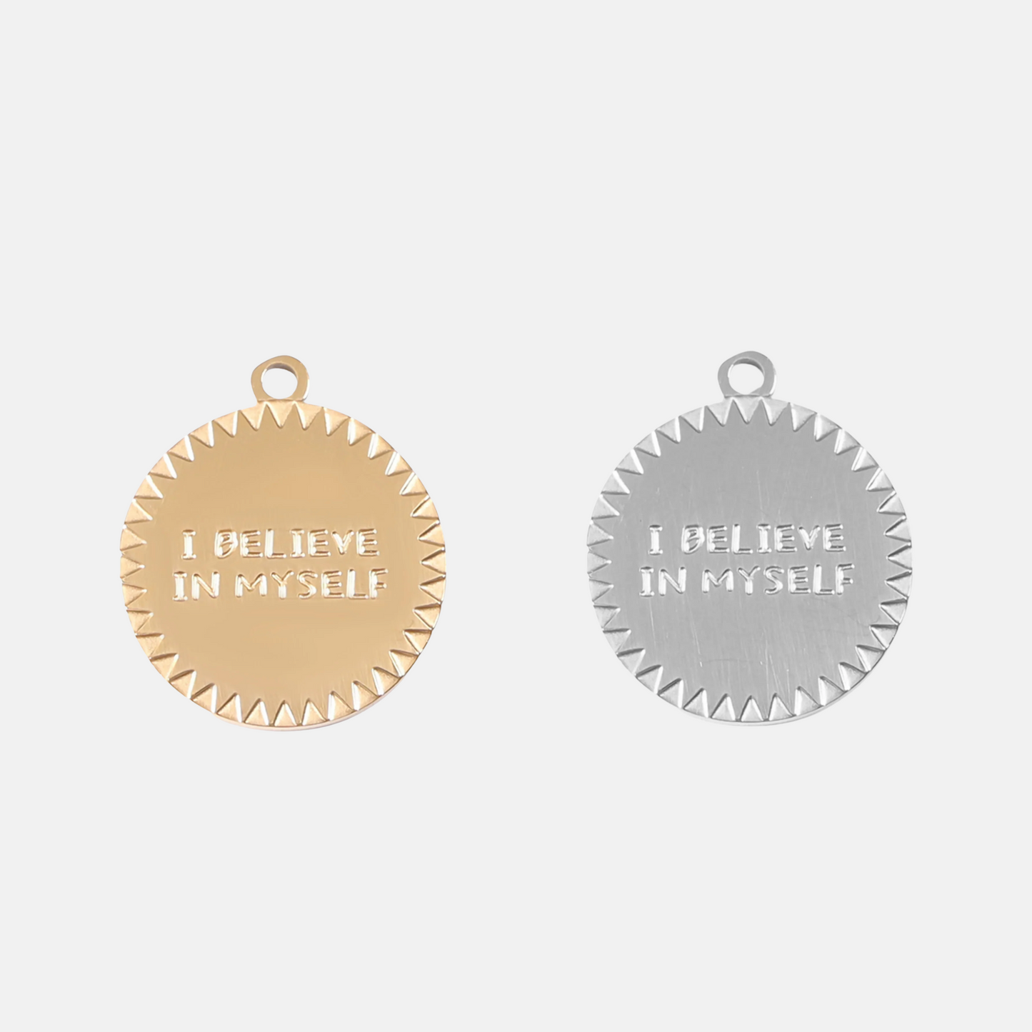 Gold and silver pendants with 'I believe in myself' text on a light gray background