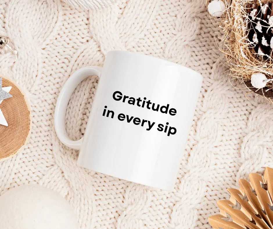 White mug with 'Gratitude in every sip' text on a textured beige surface