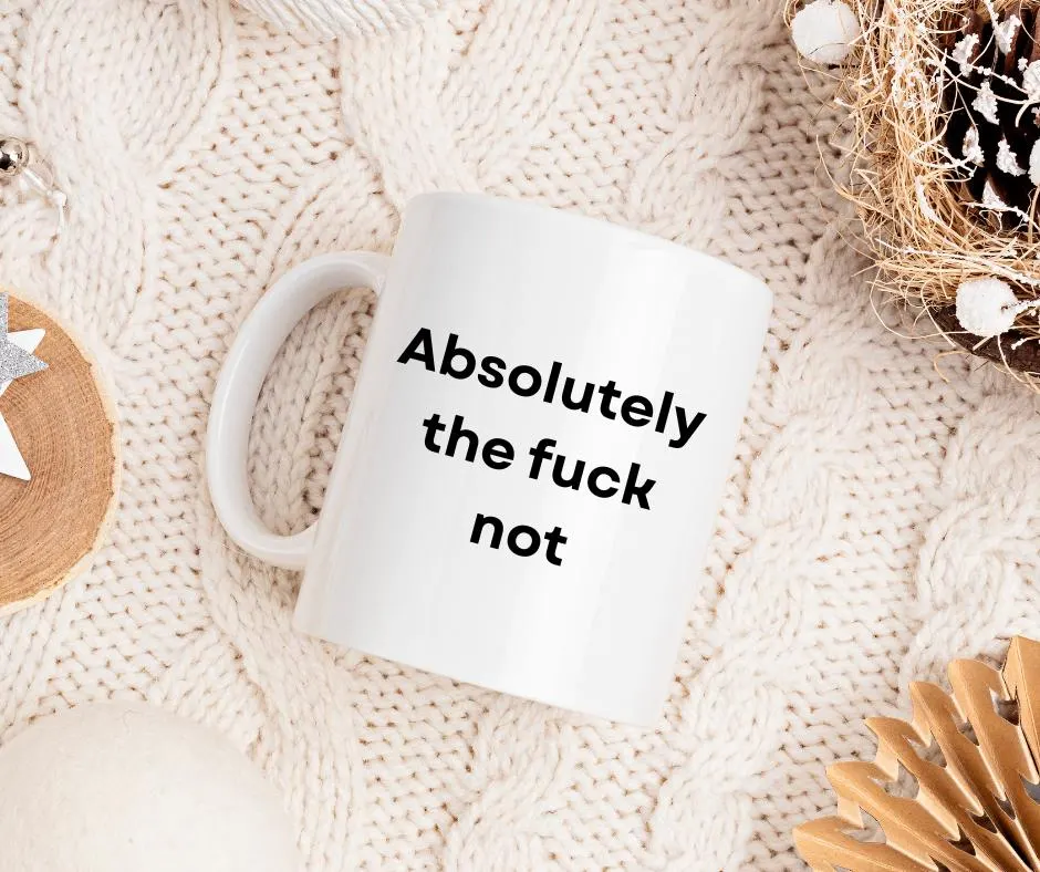 White mug with text 'Absolutely the fuck not' on a textured beige surface